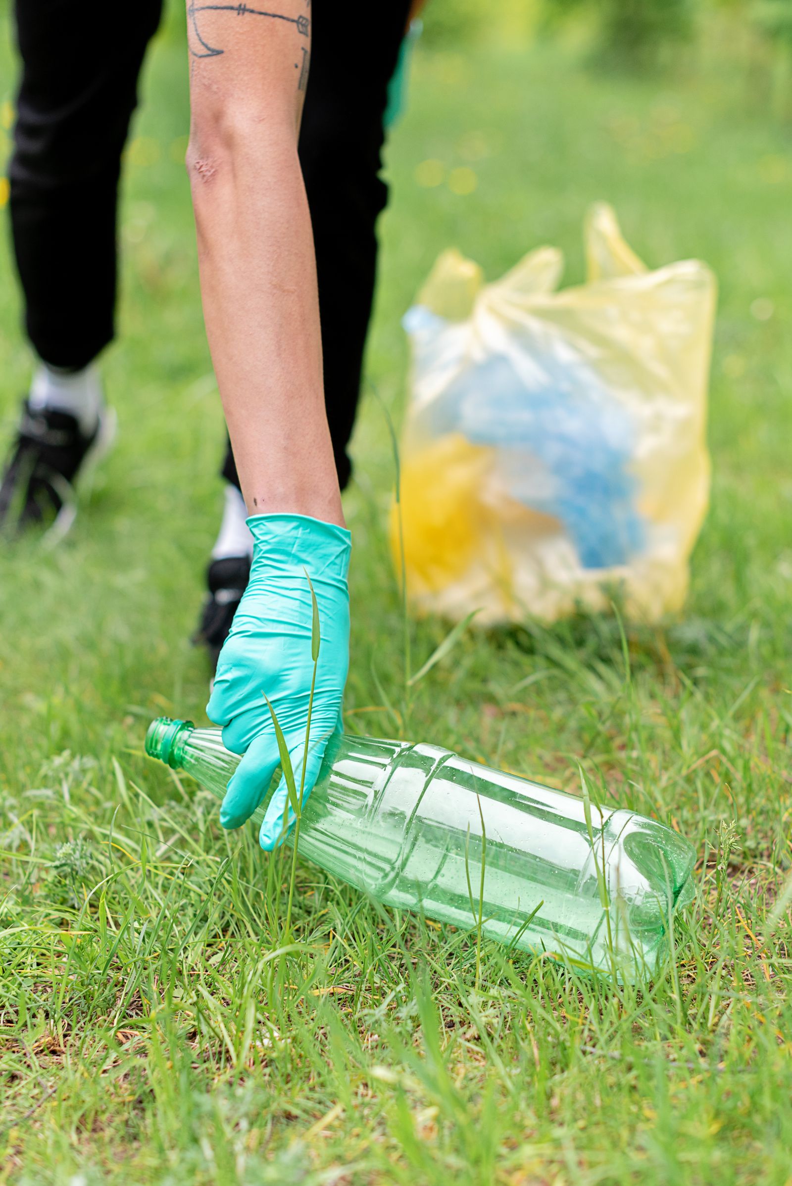 A gloved hand picking up a plastic bottle