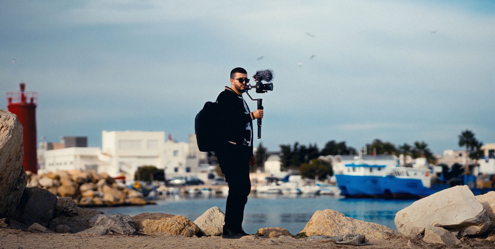 A creator filming with a gimbal-mounted camera at a harbor