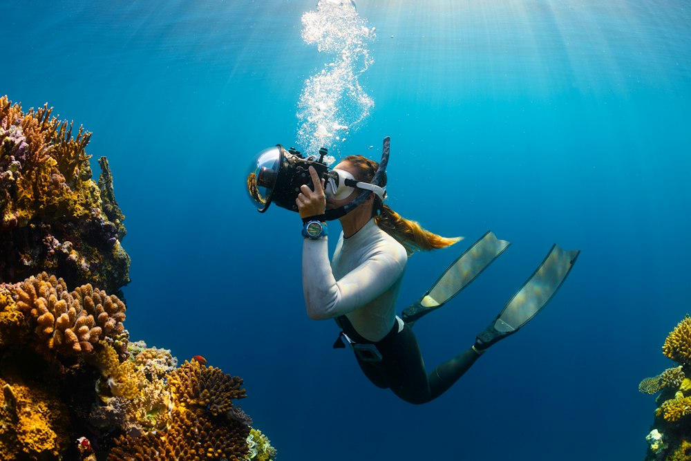 A diver filming over a coral reef